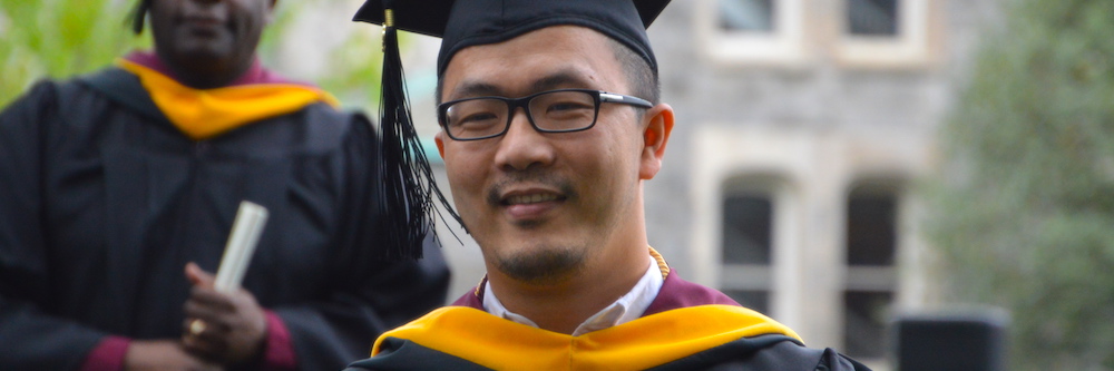 Thirty-ish Asian-American male grad student in his commencement cap and gown.