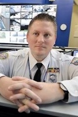 White police sergeant leaning over a counter with his hands clasped in front of him.