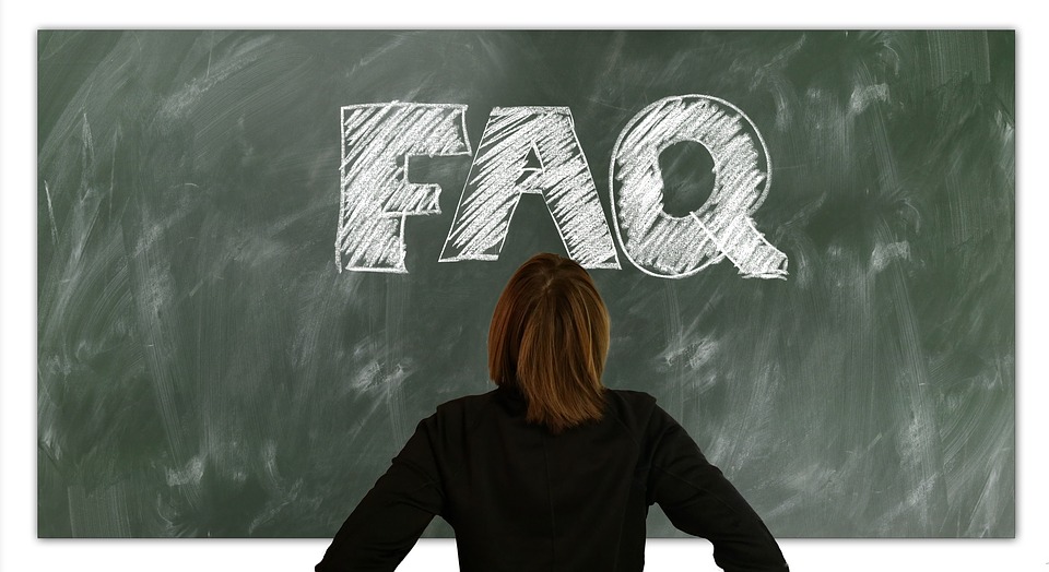 A woman with brown hair faces a blackboard on which "FAQ" is written in white chalk.