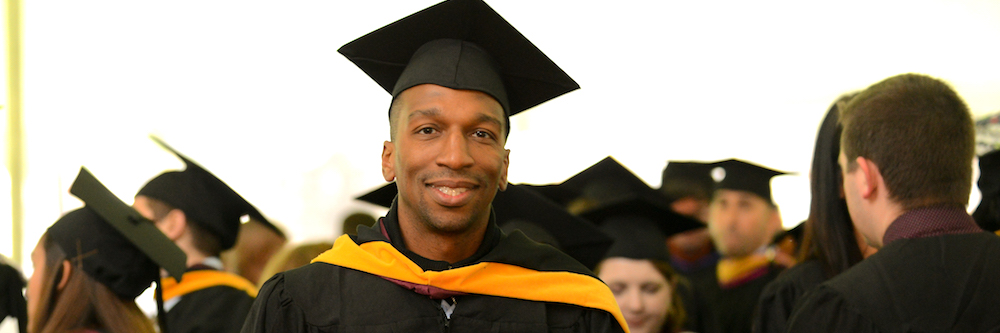 African-American man about thirty in his cap and gown at graduation.