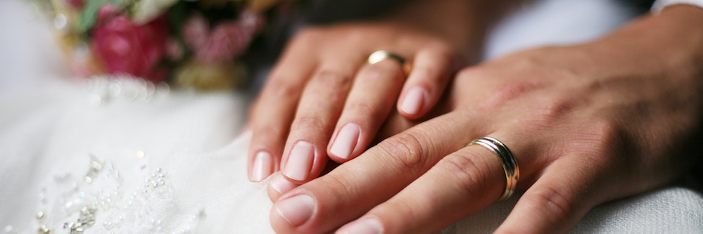 Image of a couple's hands wearing wedding rings.